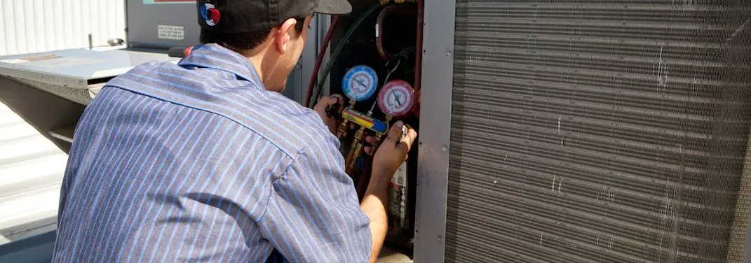 HVAC technician servicing a condenser unit in Concord